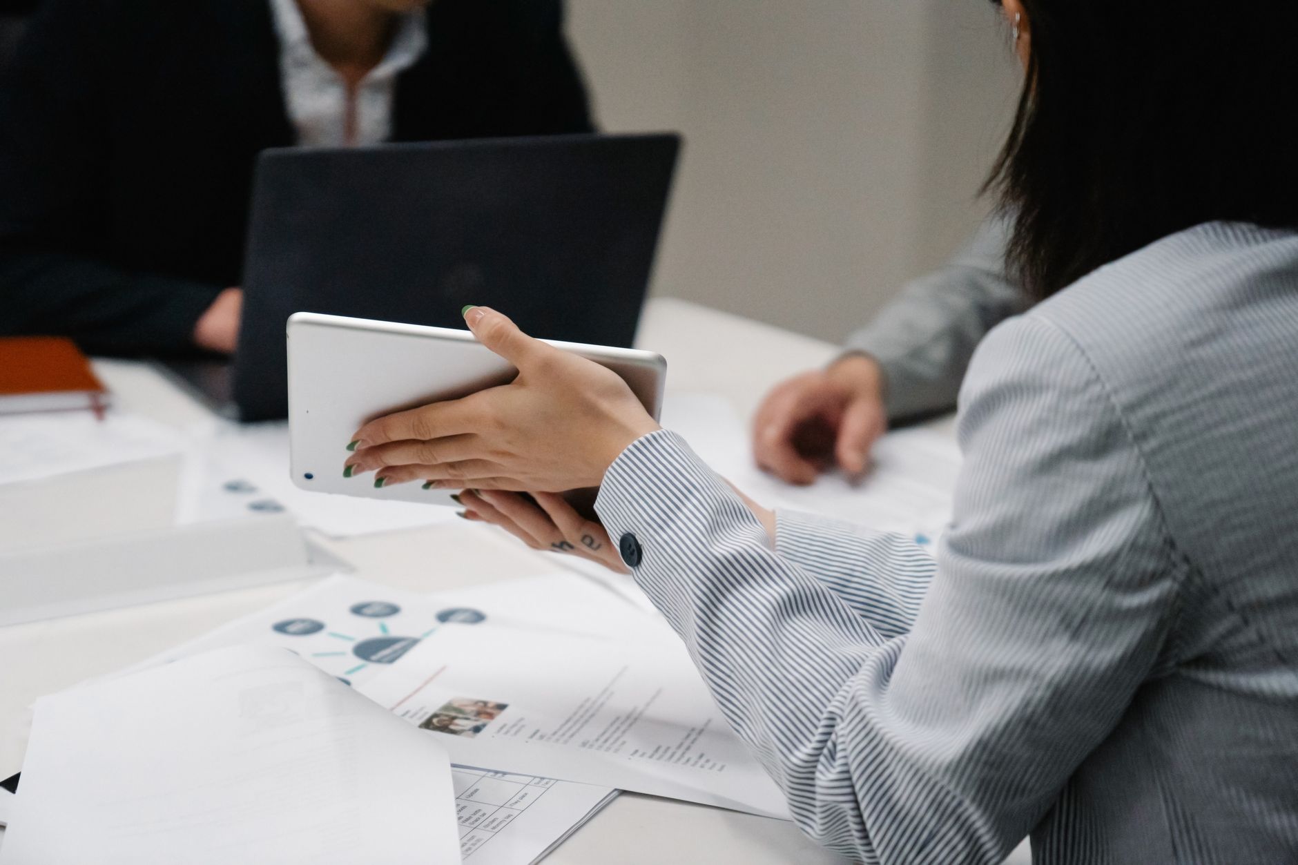 Professional business meeting with diverse team using a tablet and documents for discussion.