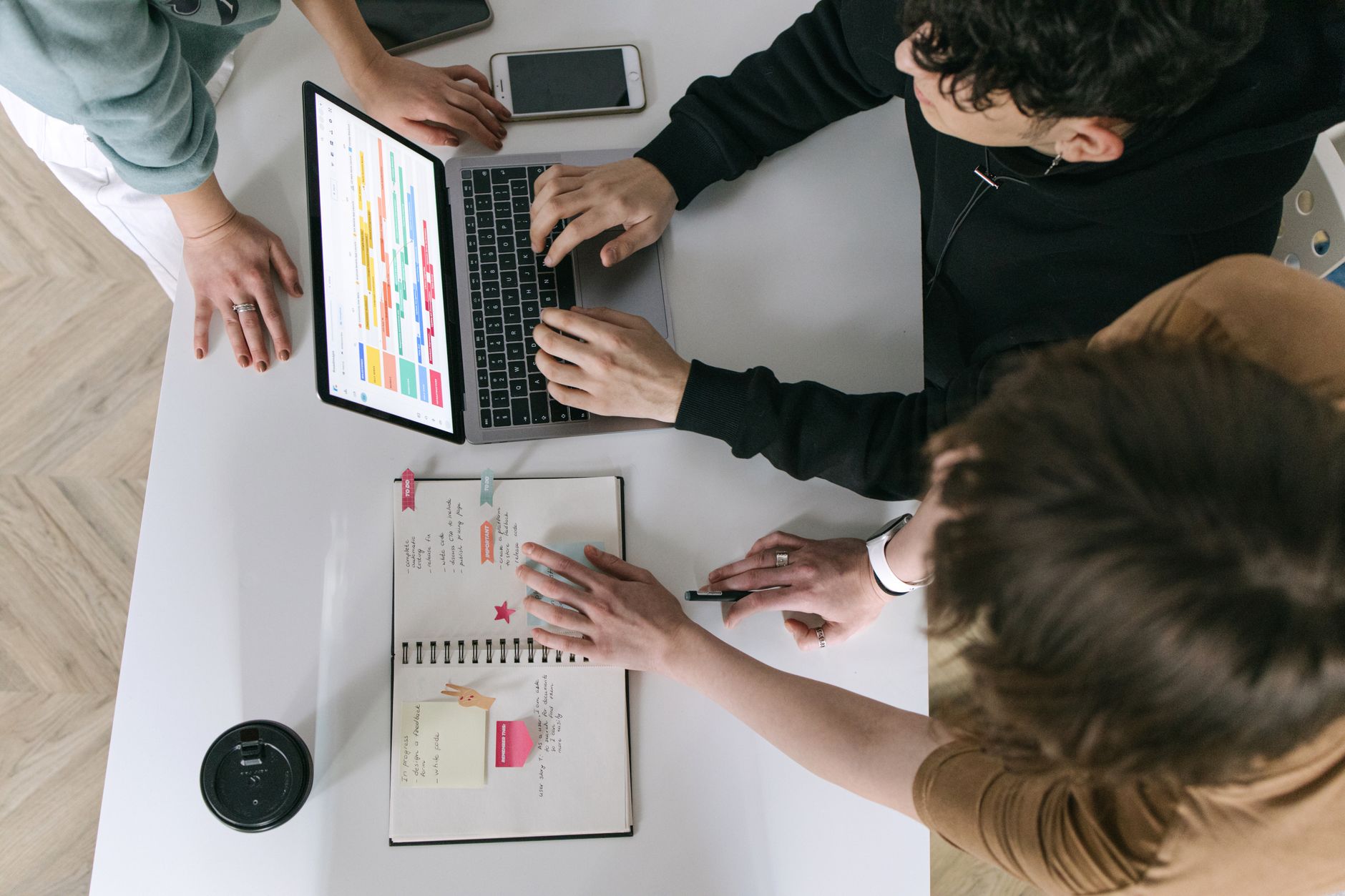 A high-angle view of a team collaborating over a laptop and notebook in a modern office.