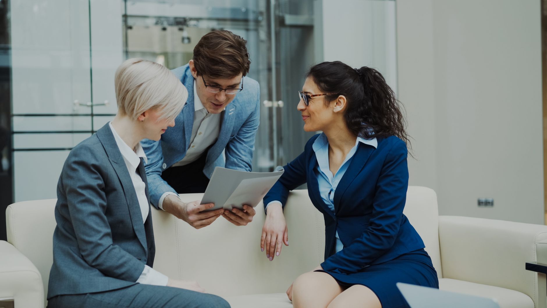 Three business professionals engaged in a meeting, collaborating over a tablet.