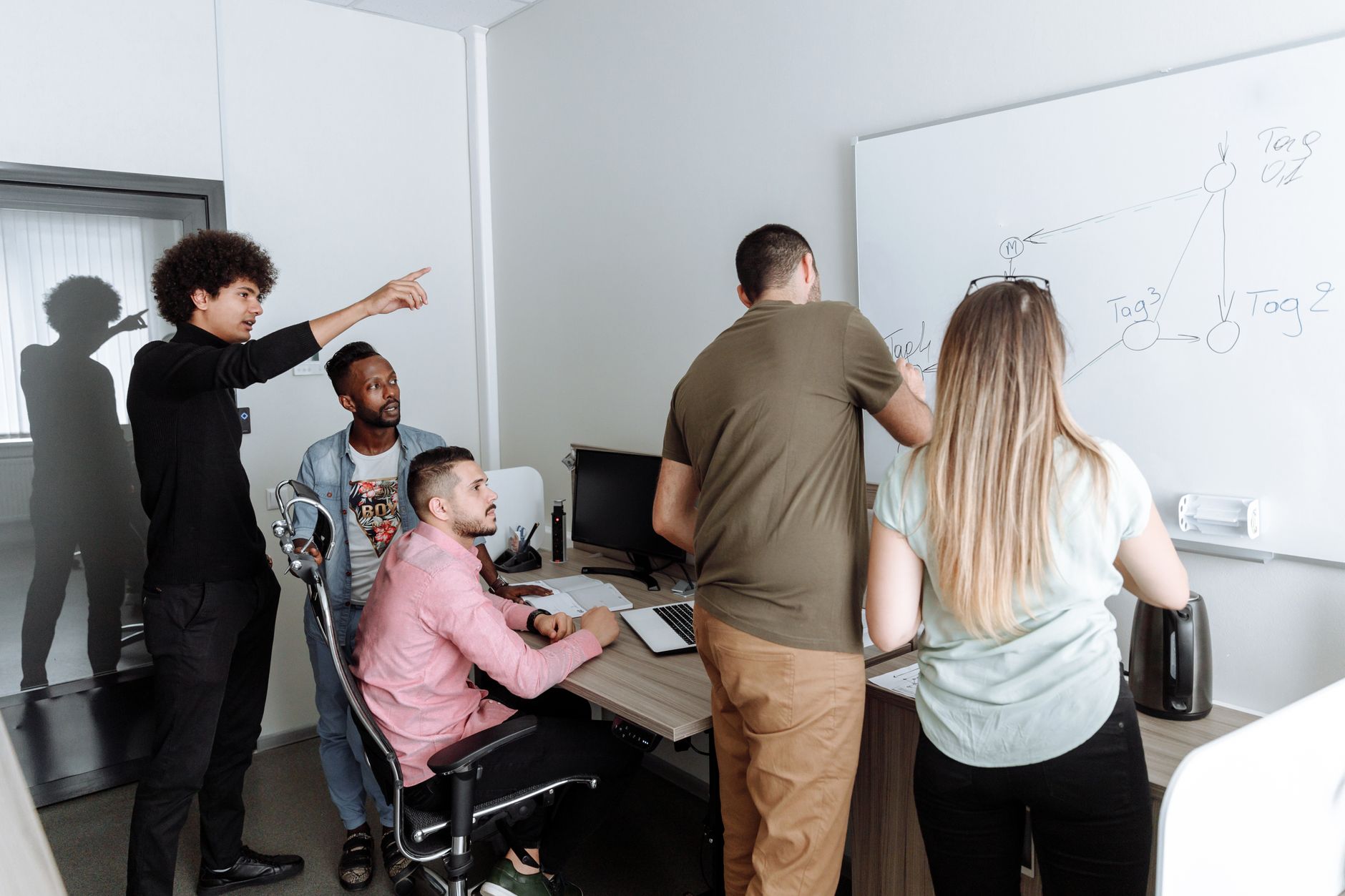A diverse group of young professionals brainstorming together in a modern office setting.