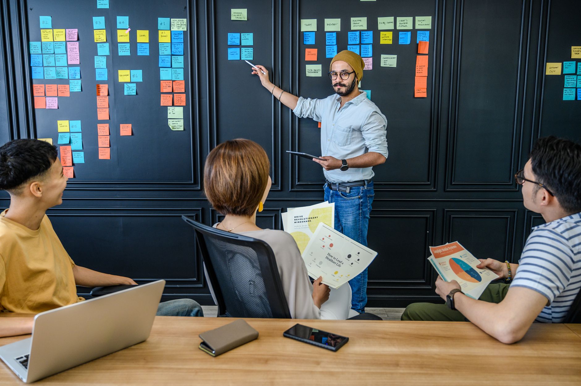 A diverse team engages in a collaborative brainstorm session with notes and presentations.