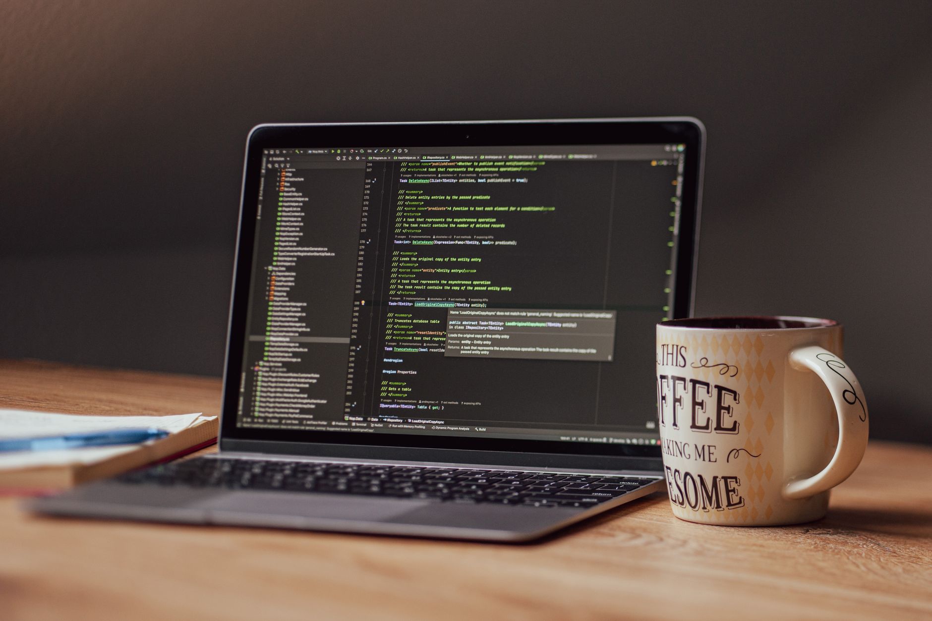 Laptop displaying code editor with coffee mug on desk, perfect for tech themes.