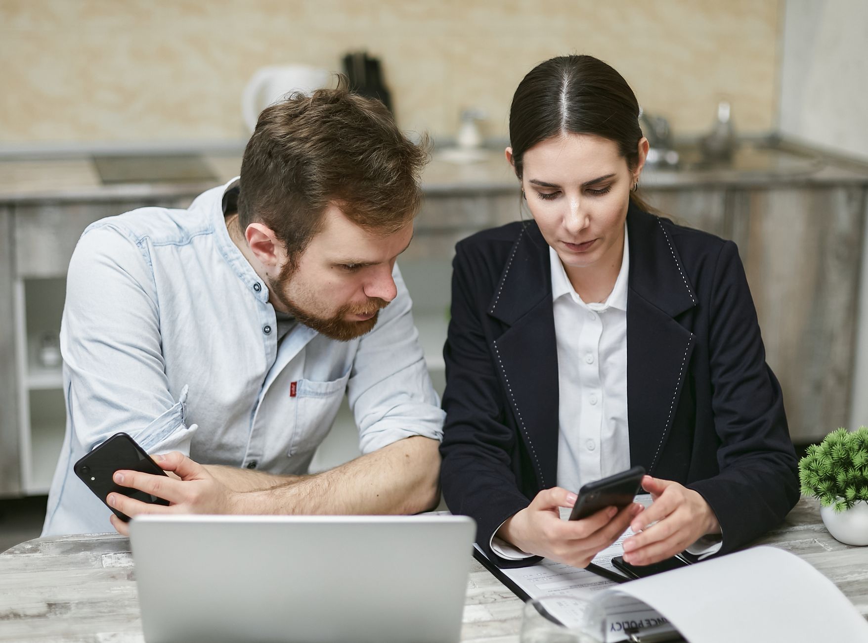 Business professionals working together using smartphones and a laptop in a modern office.